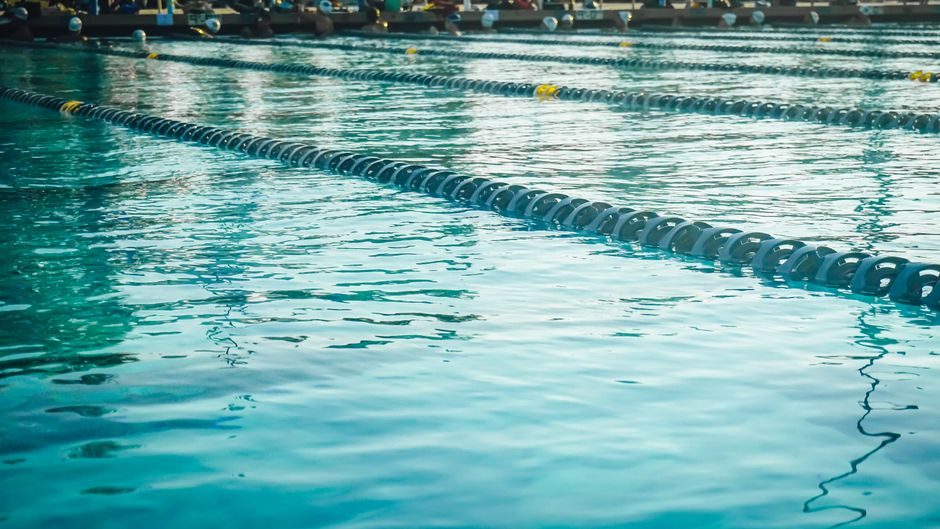 Swimmer receiving coached technique feedback beside a pool
