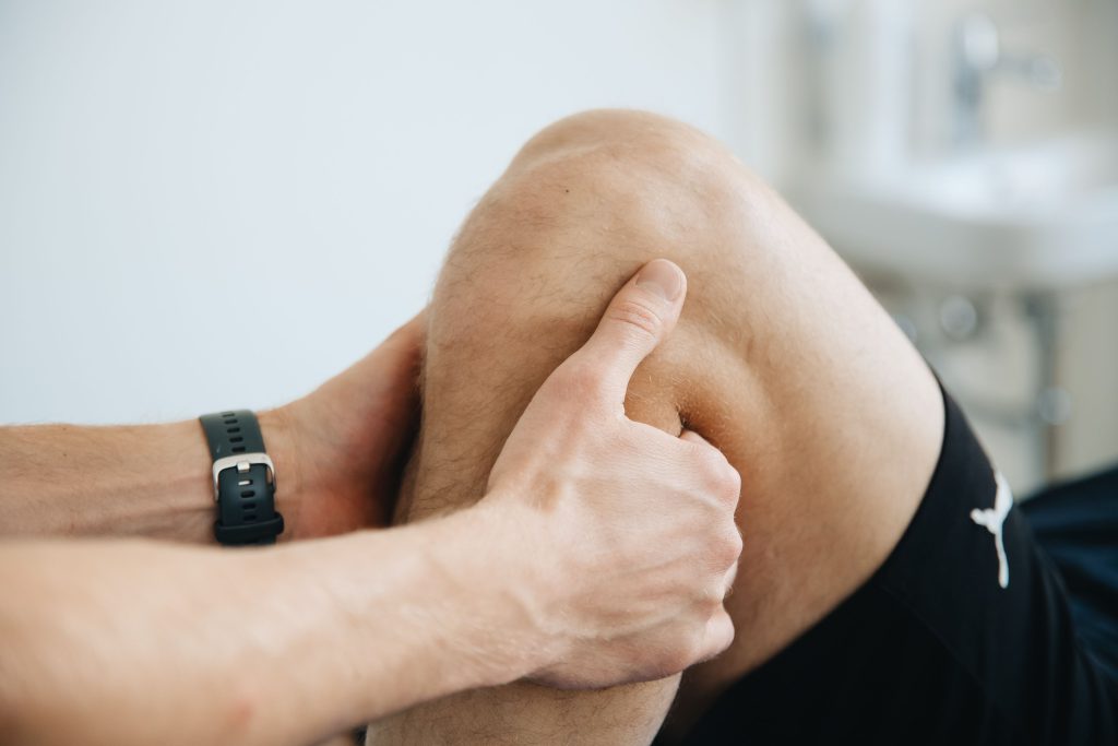 Physiotherapist assessing an athlete knee during rehabilitation