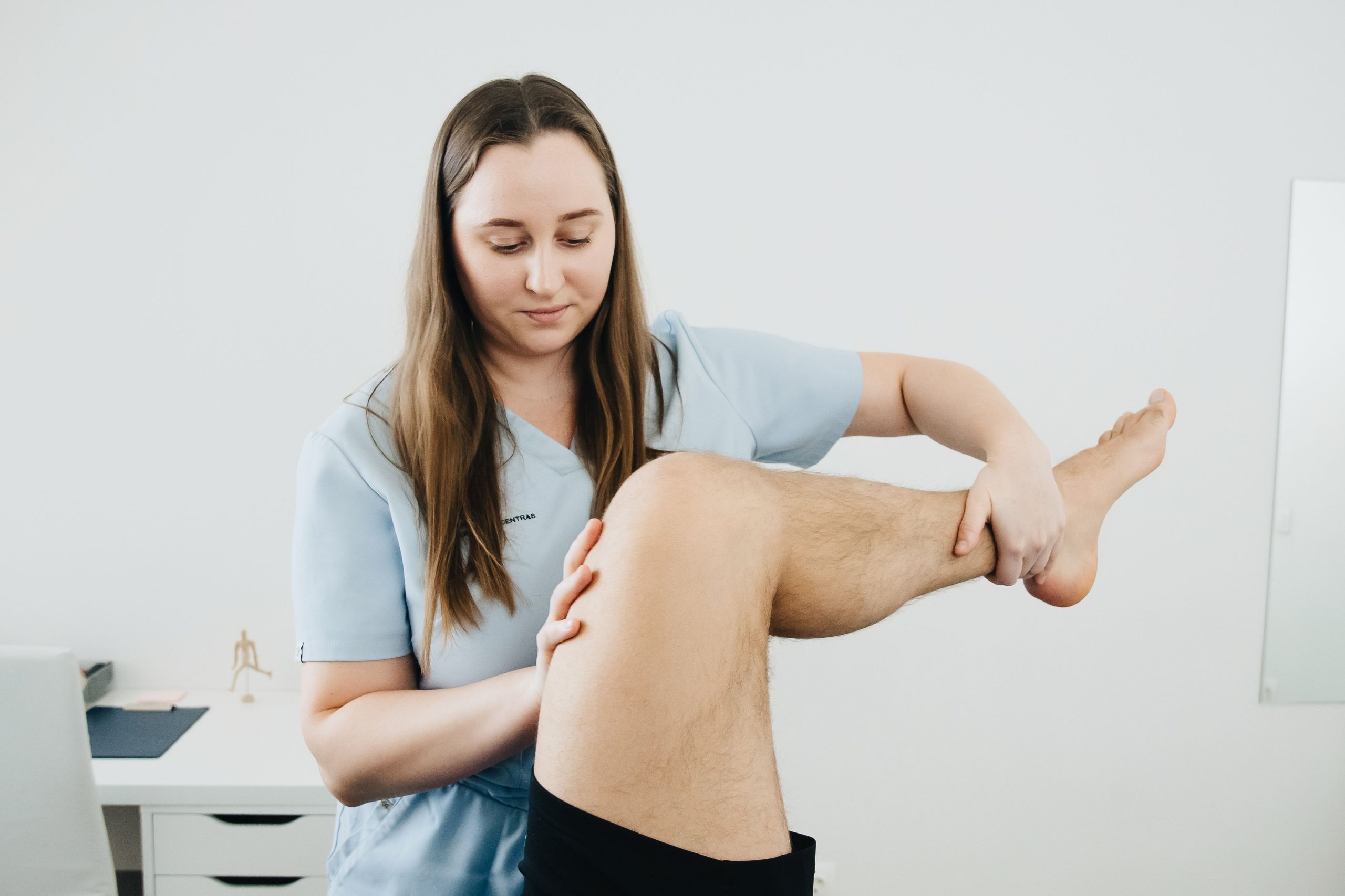 Physiotherapist guiding leg mobility during rehabilitation
