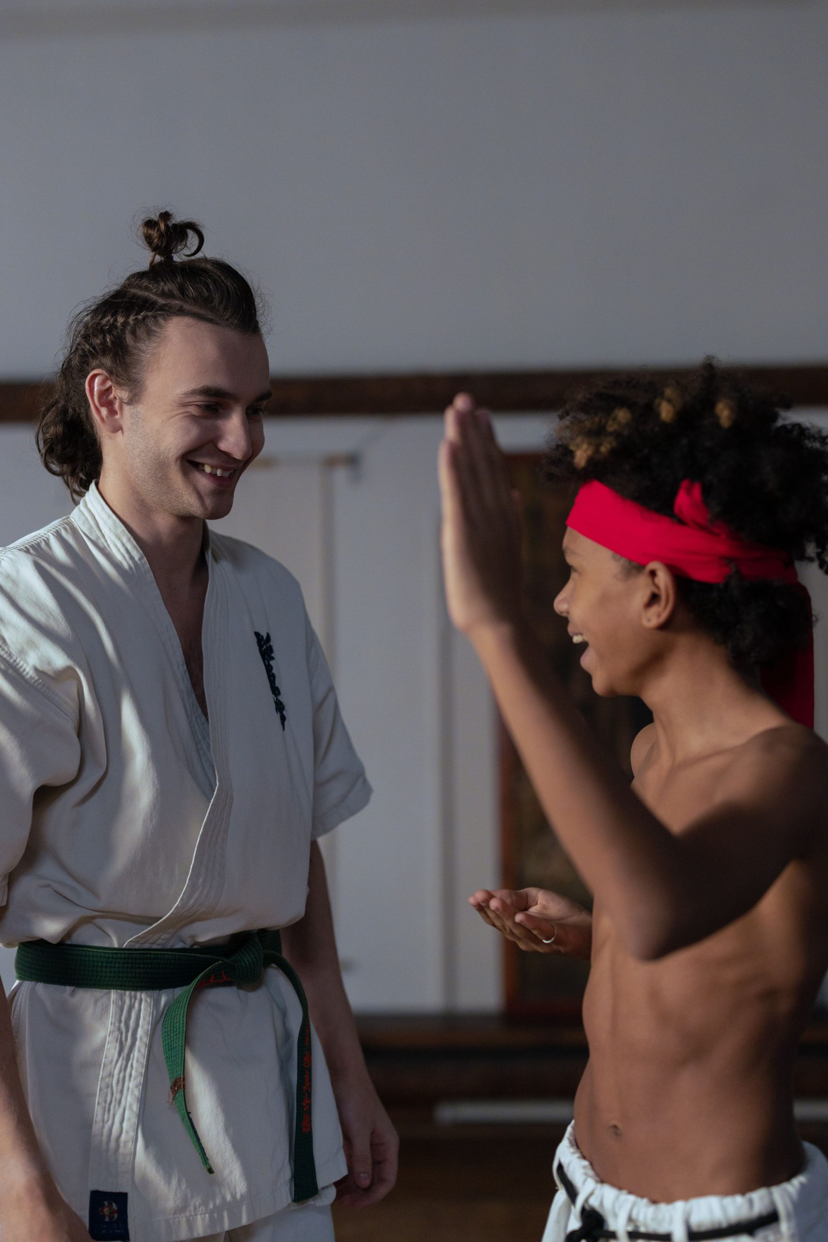 Martial arts coach and student celebrating progress in a dojo