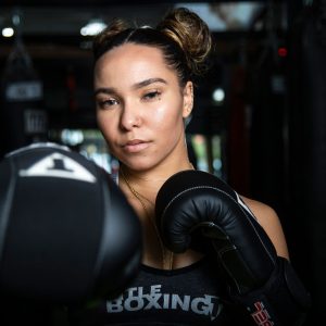 Female boxer training with gloves inside a boxing gym