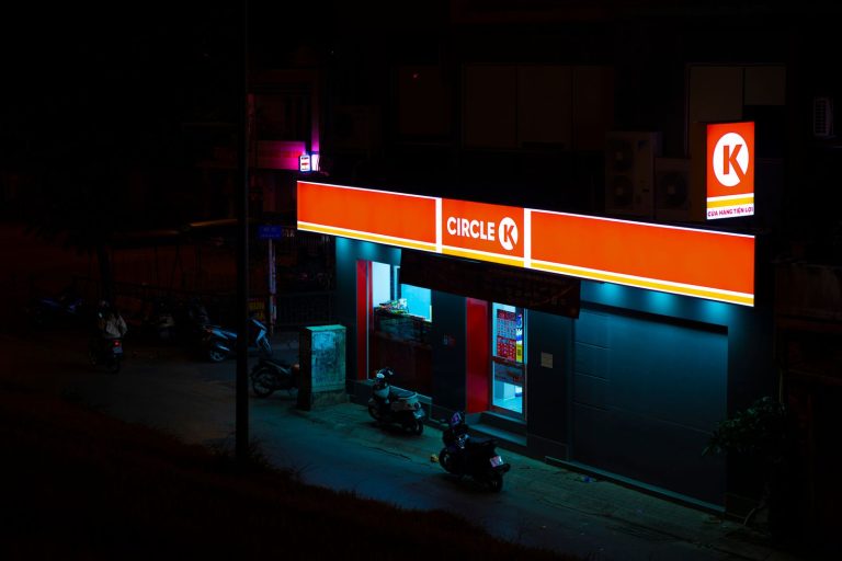 A high-angle view of a Circle K convenience store illuminated at night, with motorcycles parked outside.