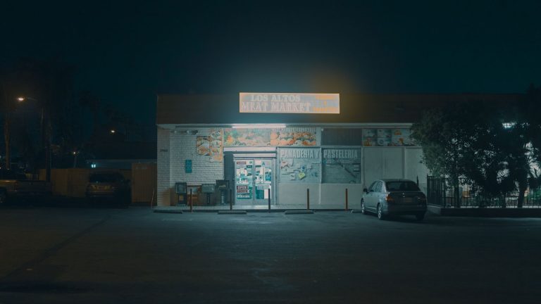 Night view of an illuminated meat market with parked cars, exuding a calm and urban atmosphere.