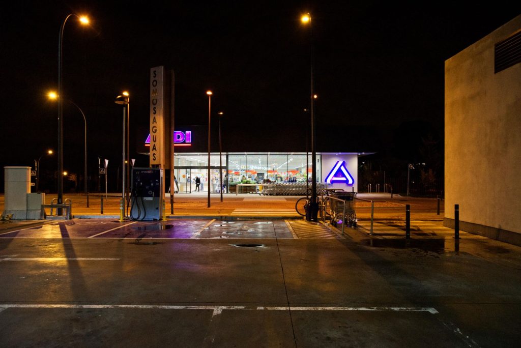 Illuminated gas station and supermarket at night in Madrid, showcasing urban nightlife.
