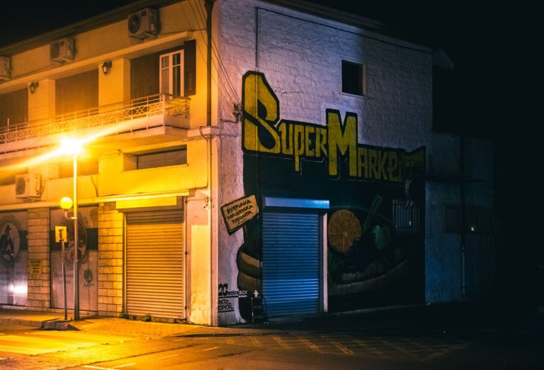 Night scene showcasing graffiti on a closed supermarket with warm street lighting.