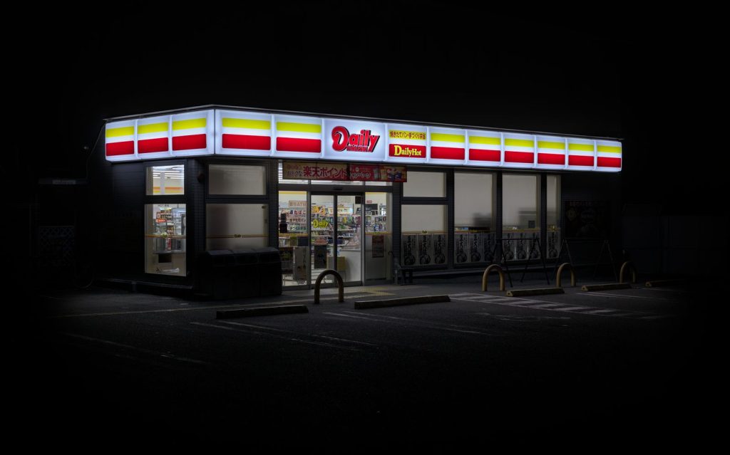 Exterior of a brightly lit convenience store in Kyoto, Japan during night.