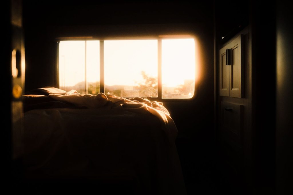 Tranquil bedroom interior bathed in warm sunrise light through the window, creating a serene atmosphere.