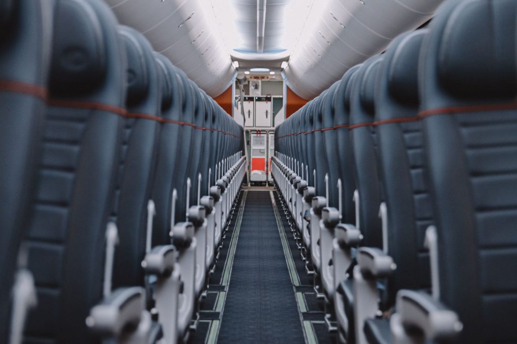 View down the aisle of an empty airplane cabin showcasing seats and overhead compartments.