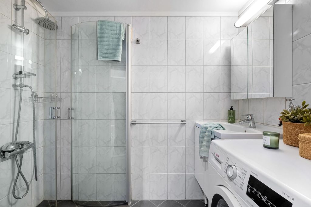 Clean and minimalistic bathroom featuring a shower, sink, and laundry area.