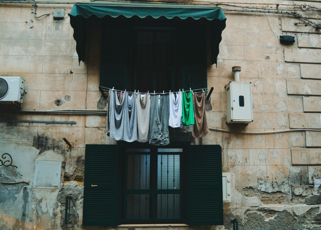 Laundry drying on a balcony string against an old textured building facade.
