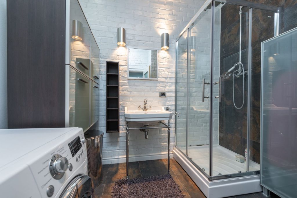 Sleek and contemporary bathroom showcasing a shower cabin, sink, and washing machine.