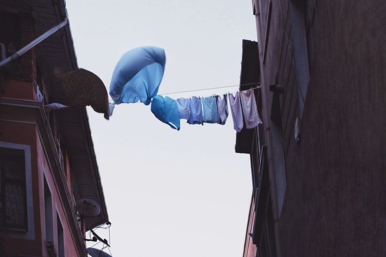 Laundry hanging on a rope between buildings in an urban setting, drying under the sky.