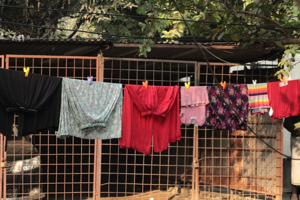 Various colorful clothes hanging on a clothesline outside in sunny weather.