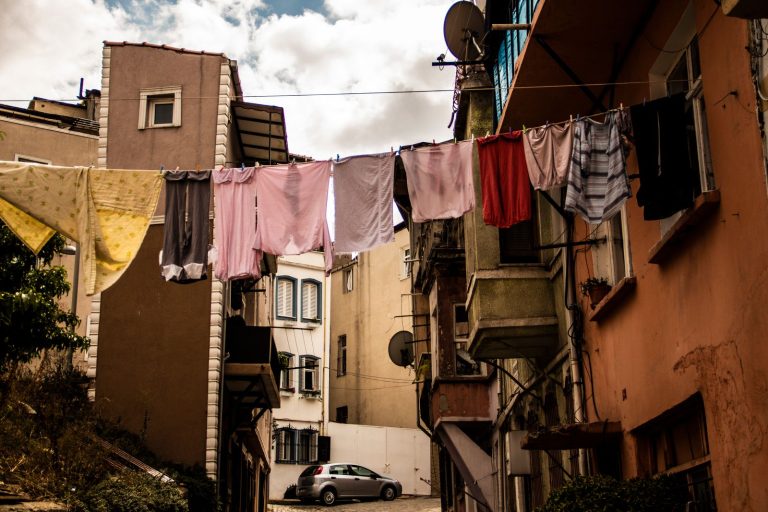 Charming urban scene of clothes hanging on a line between buildings under a cloudy sky.