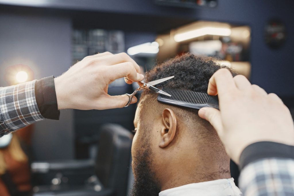 Close-up of a barber giving a haircut with scissors and comb in a modern salon.