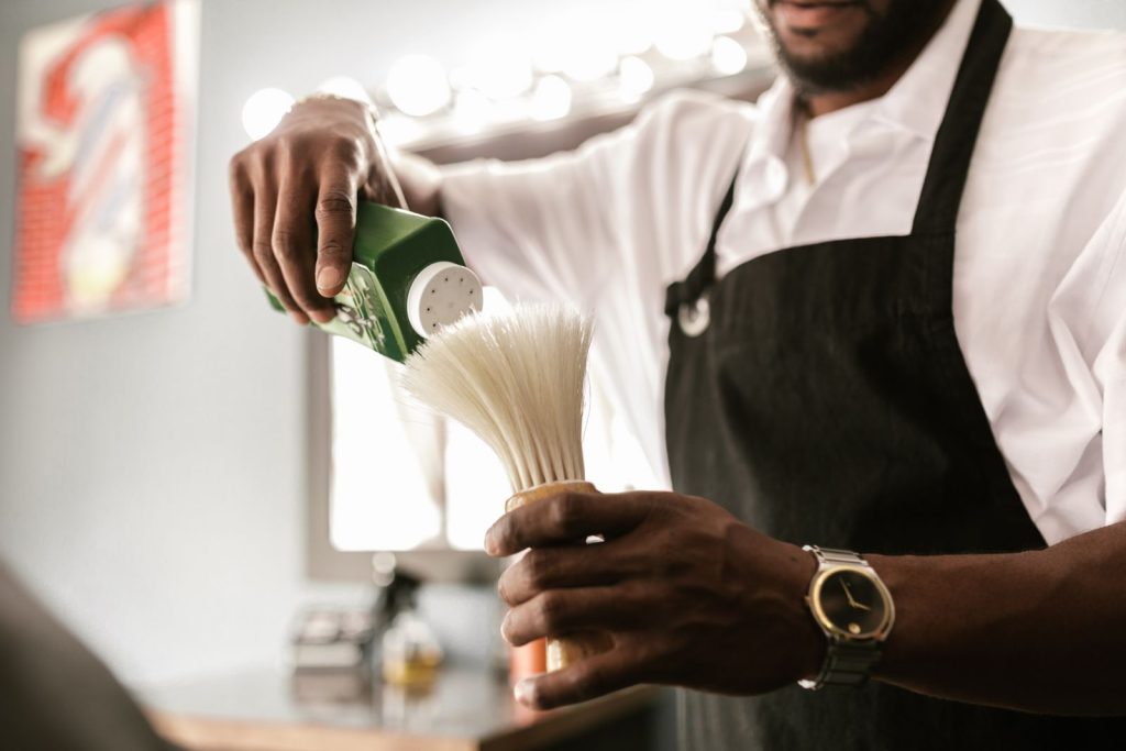 Barber in a shop preparing tools with powder for a haircut.