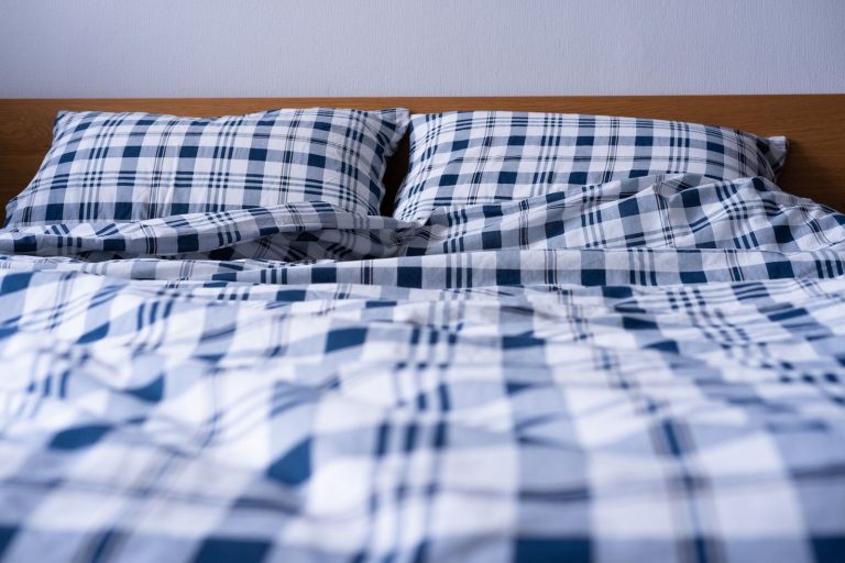 Comfortable double bed with blue plaid pattern bedding in a modern bedroom setting.