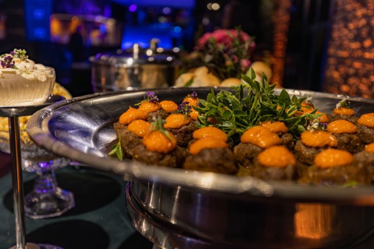 Elegant display of gourmet dishes at a banquet with vibrant lighting and luxurious ambiance.
