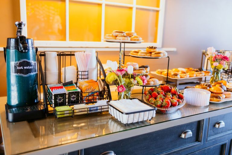 Bright breakfast buffet with donuts, strawberries, tea, and hot water setup.