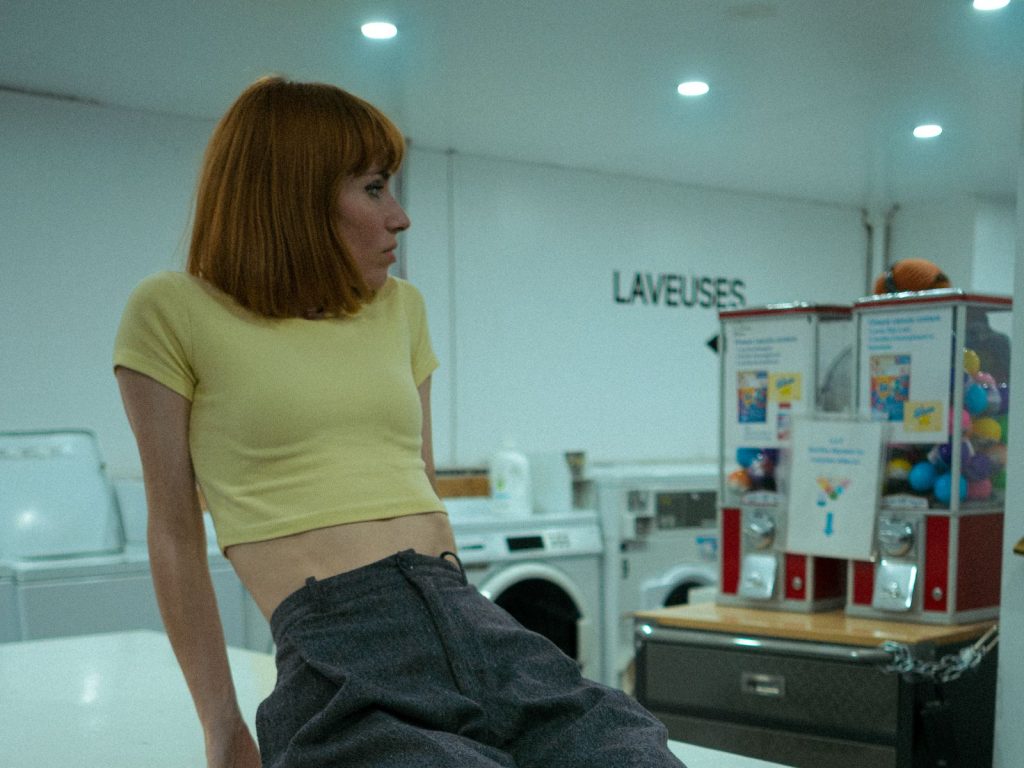 Portrait of a fashionable woman in a Montréal laundromat, exuding a retro vibe.