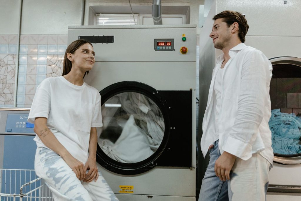 A man and woman casually chatting in a contemporary laundromat setting.