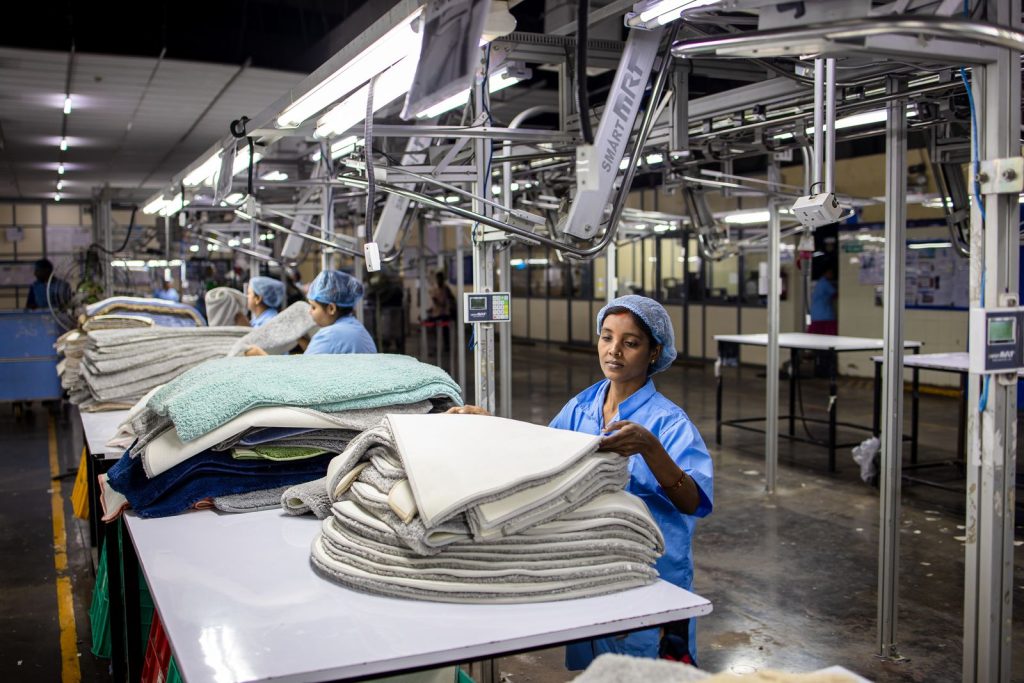 Workers sorting and stacking textiles in an indoor factory setting, showcasing industrial efficiency.