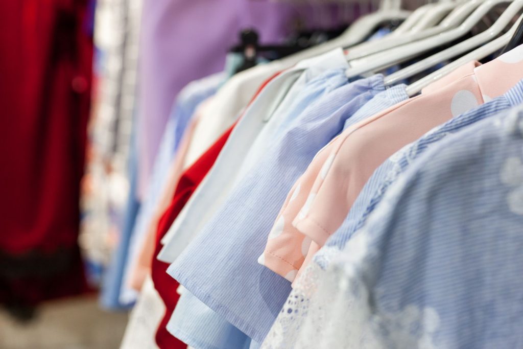Row of assorted female clothes with ornament hanging on racks in boutique on blurred background