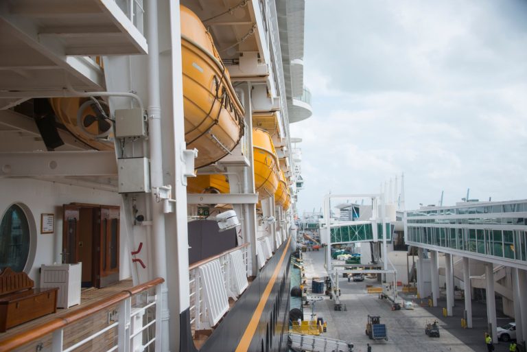 A detailed view of life boats on a docked cruise ship at a port, showcasing maritime safety equipment and infrastructure.