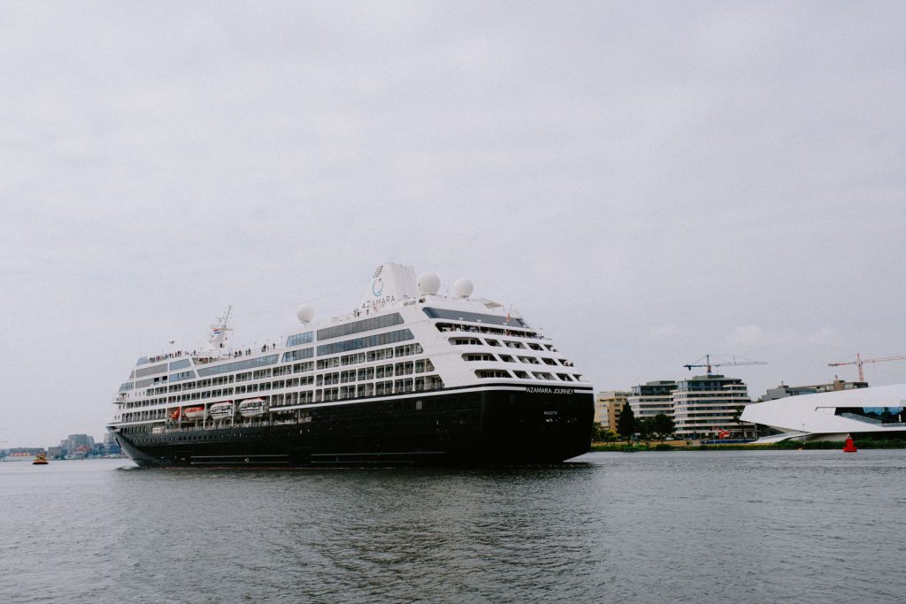 A luxury cruise ship stationed in a city harbor, surrounded by modern architecture.