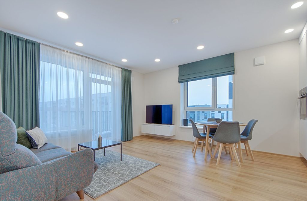 Spacious and stylish living room with dining area in a modern Lithuanian apartment.