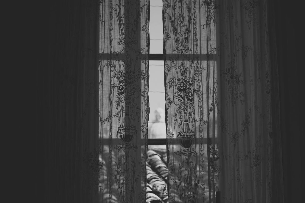 Black and white image of lace curtains framing a rooftop view. Elegant and timeless interior decor.