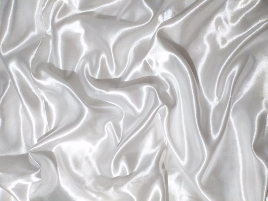 Close-up of a luxurious white silk fabric showcasing its smooth and glossy texture.