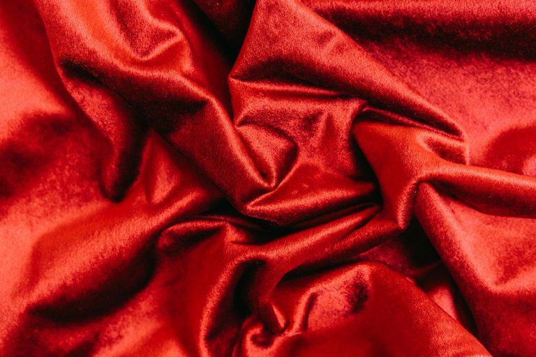 Close-up of crumpled red velvet fabric, showcasing its smooth and glossy texture.