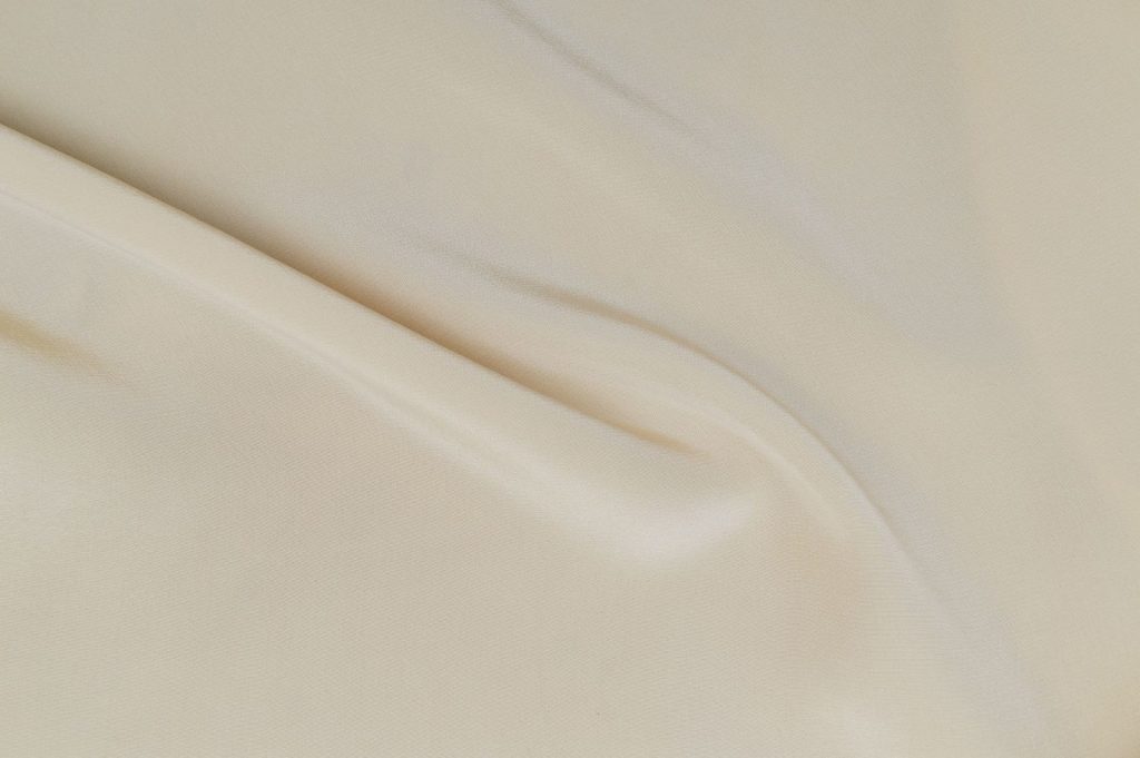 Elegant close-up view of white silk fabric, showcasing smooth texture and soft folds.