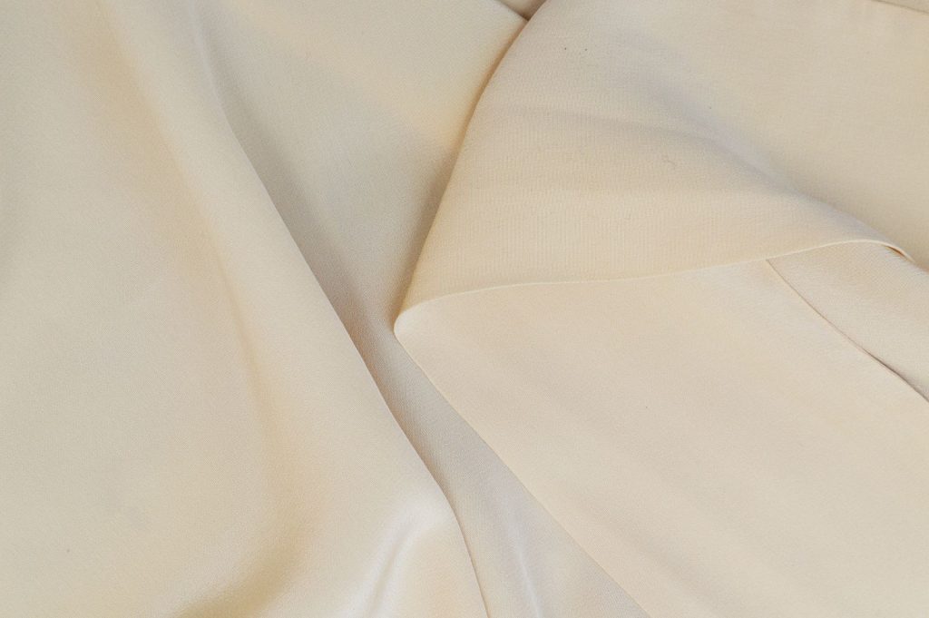 Close-up of elegant cream-colored textile folds with smooth texture, perfect for backgrounds.