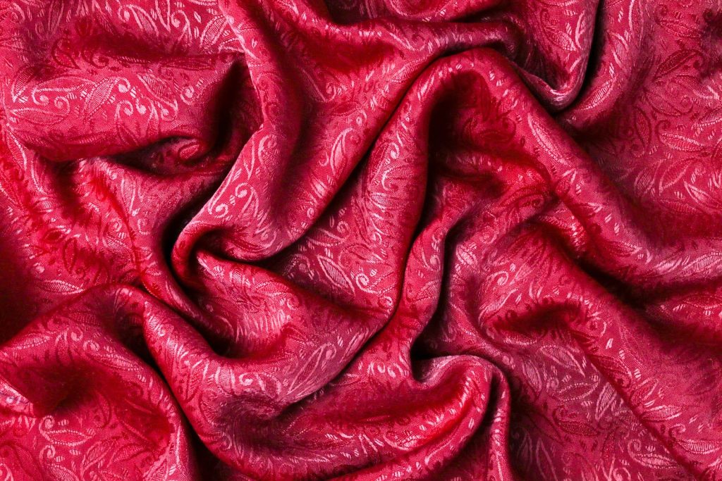 Vibrant close-up of red fabric with intricate patterns and soft folds.