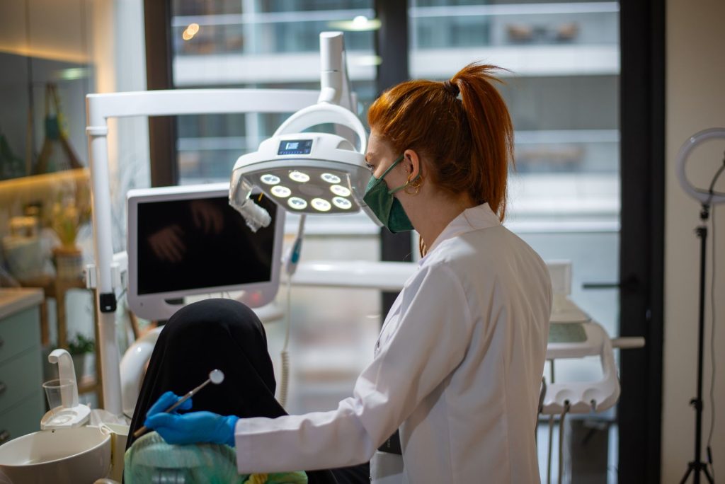 A dentist wearing a mask attends to a patient in a modern dental clinic with advanced equipment.