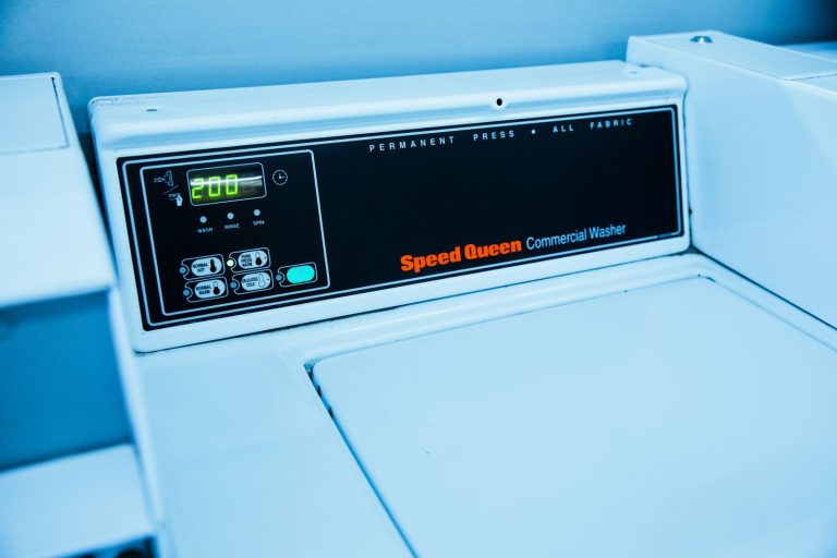 Close-up of Speed Queen commercial washing machine controls in a laundromat setting.