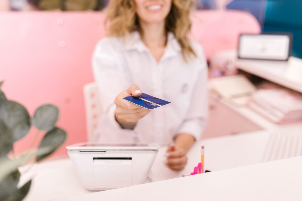 Blurred hands offering a credit card to a cashier at a modern retail counter.