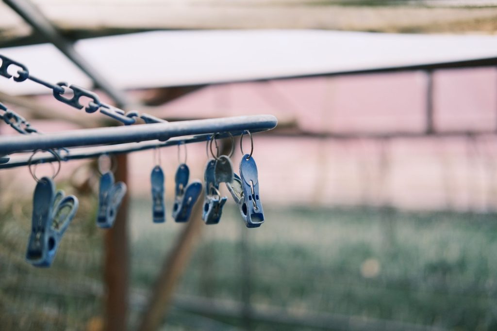 Close-up of blue clothespins on a chain outdoors, ideal for summer laundry themes.