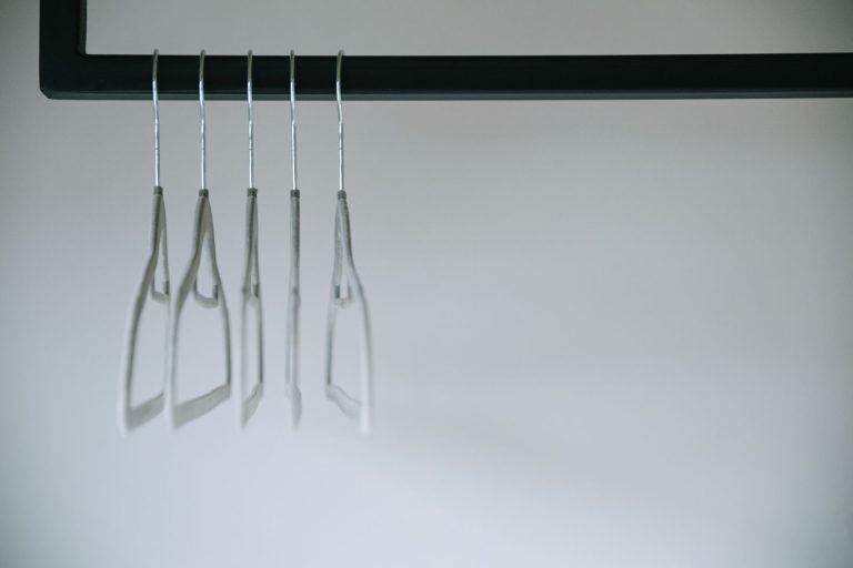 A minimalist shot of clothes hangers on a rack against a white background, highlighting simplicity.