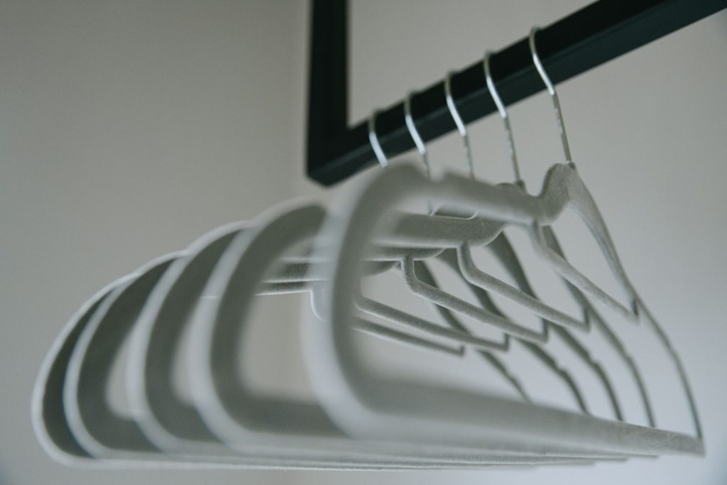 Close-up view of minimalist felt coat hangers on a clothes rack, showcasing simple design.