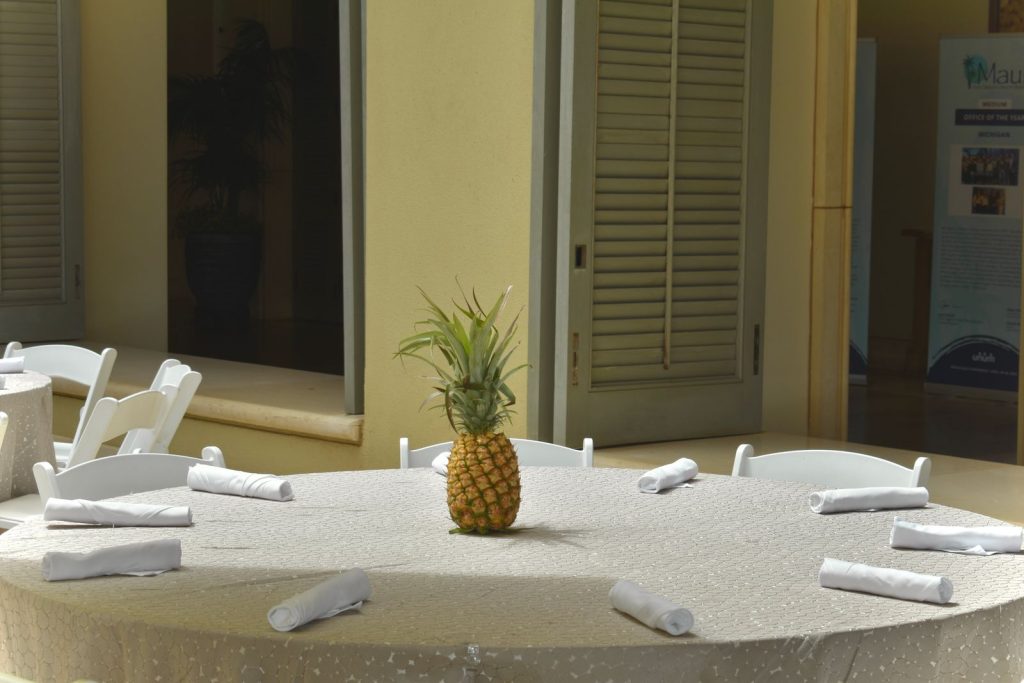 Indoor table setting with a pineapple centerpiece and elegant white napkins.
