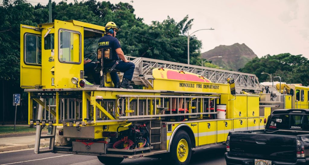 Firefighter seated on a yellow fire truck in Honolulu, Hawaii, ready for action.