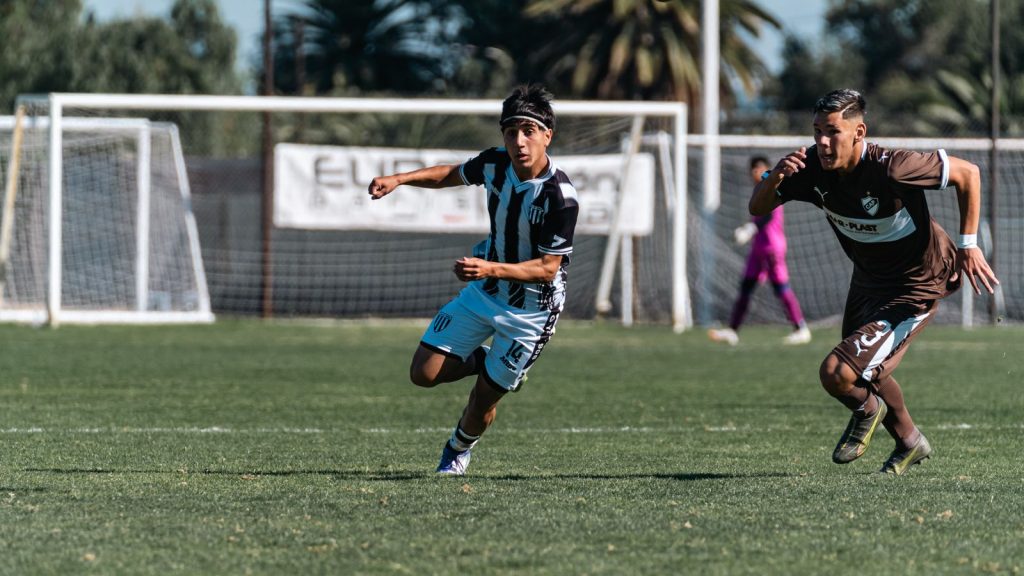 Two young male soccer players sprinting during an intense outdoor match on a sunny day.