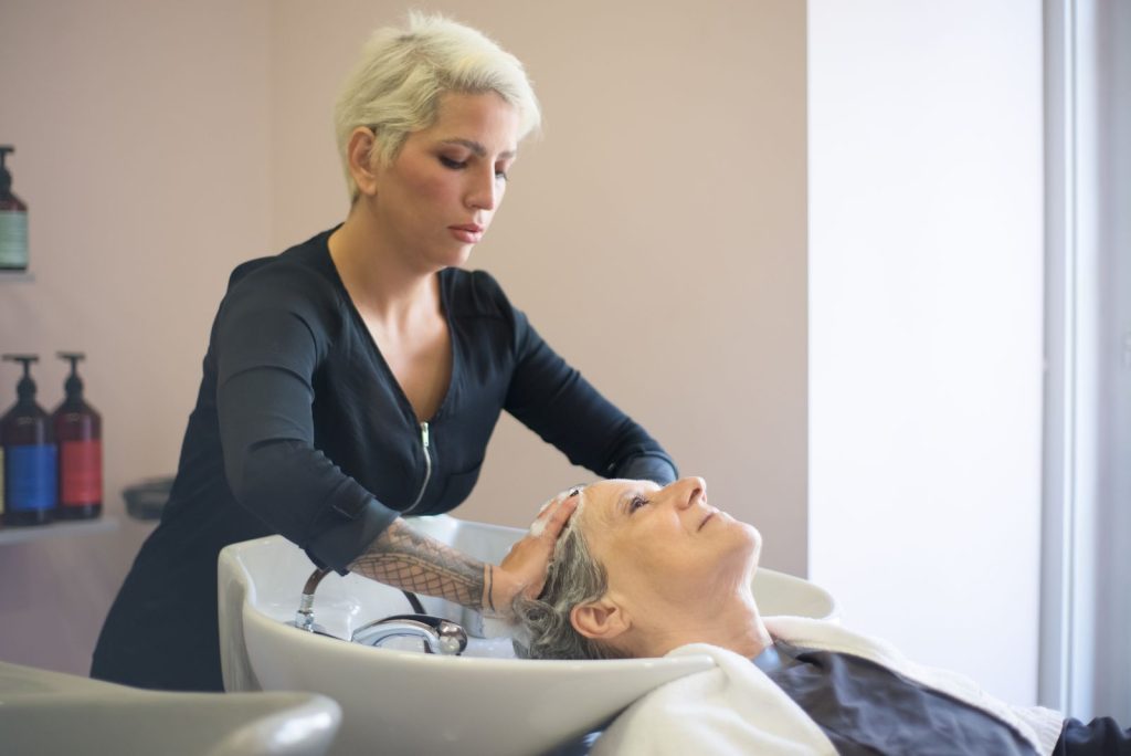 A hairdresser providing a relaxing hair wash to a senior woman in a salon setting.