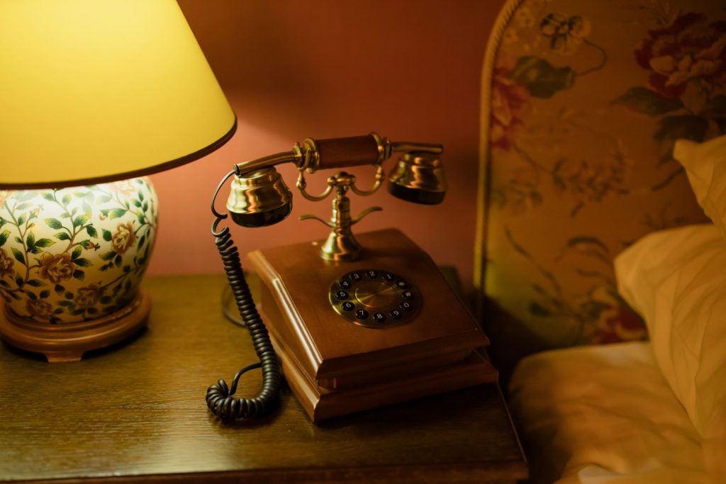 Classic hotel room decor featuring an antique telephone and floral lamp.