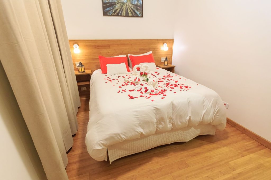 A romantic bedroom setup with soft lighting, rose petals, and plush bedding for a cozy ambience.