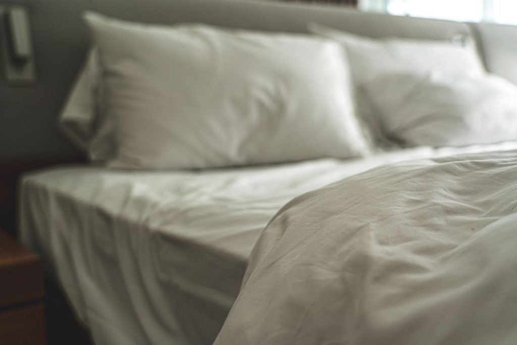 Elegant white bed linen with soft pillows creating a warm and inviting atmosphere.