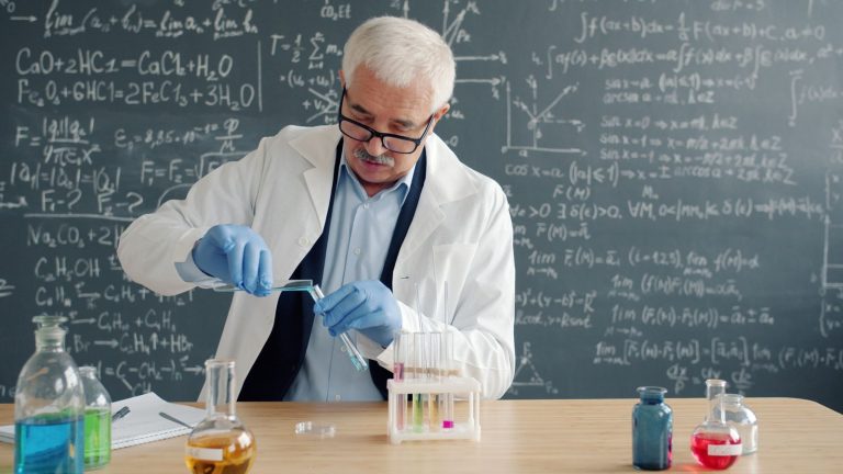 Scientist in lab coat performing experiment with test tubes in laboratory.